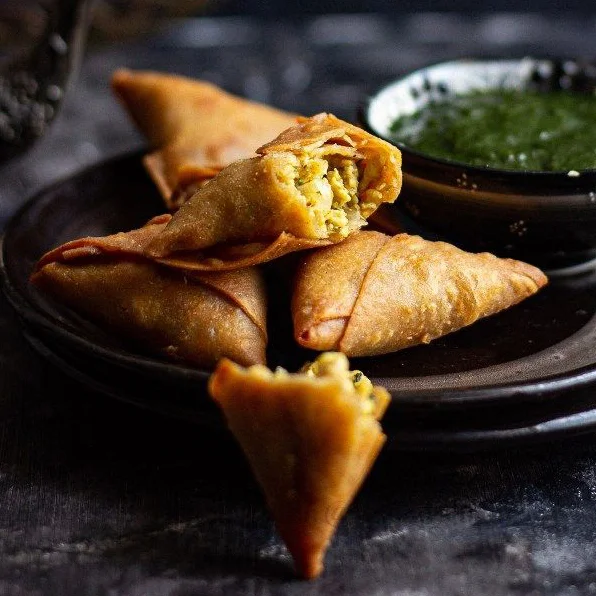 Golden sambusas served with dipping sauce